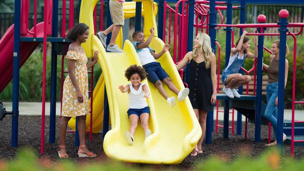 Niños deslizándose por toboganes mientras juegan con sus mamás en el parque infantil Golden Bear Park.