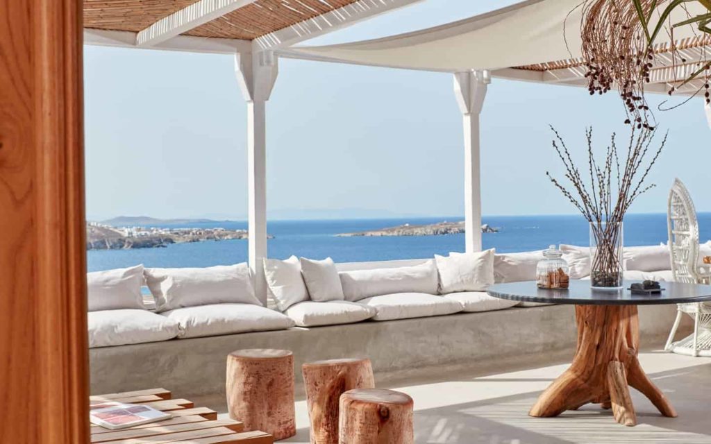 Balcón cubierto de la suite Boheme Mykonos con lujosos asientos y vistas al mar