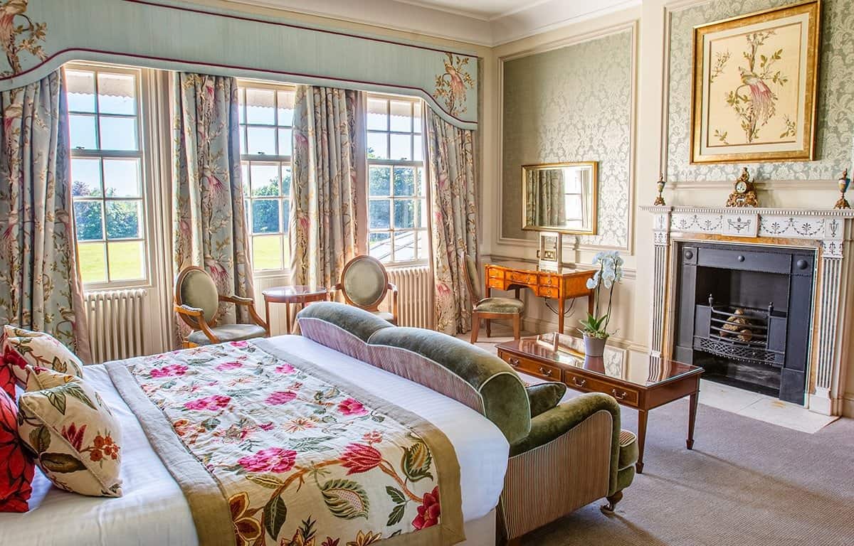 Brockencote Hall Hotel bedroom with fireplace and expansive view of grounds