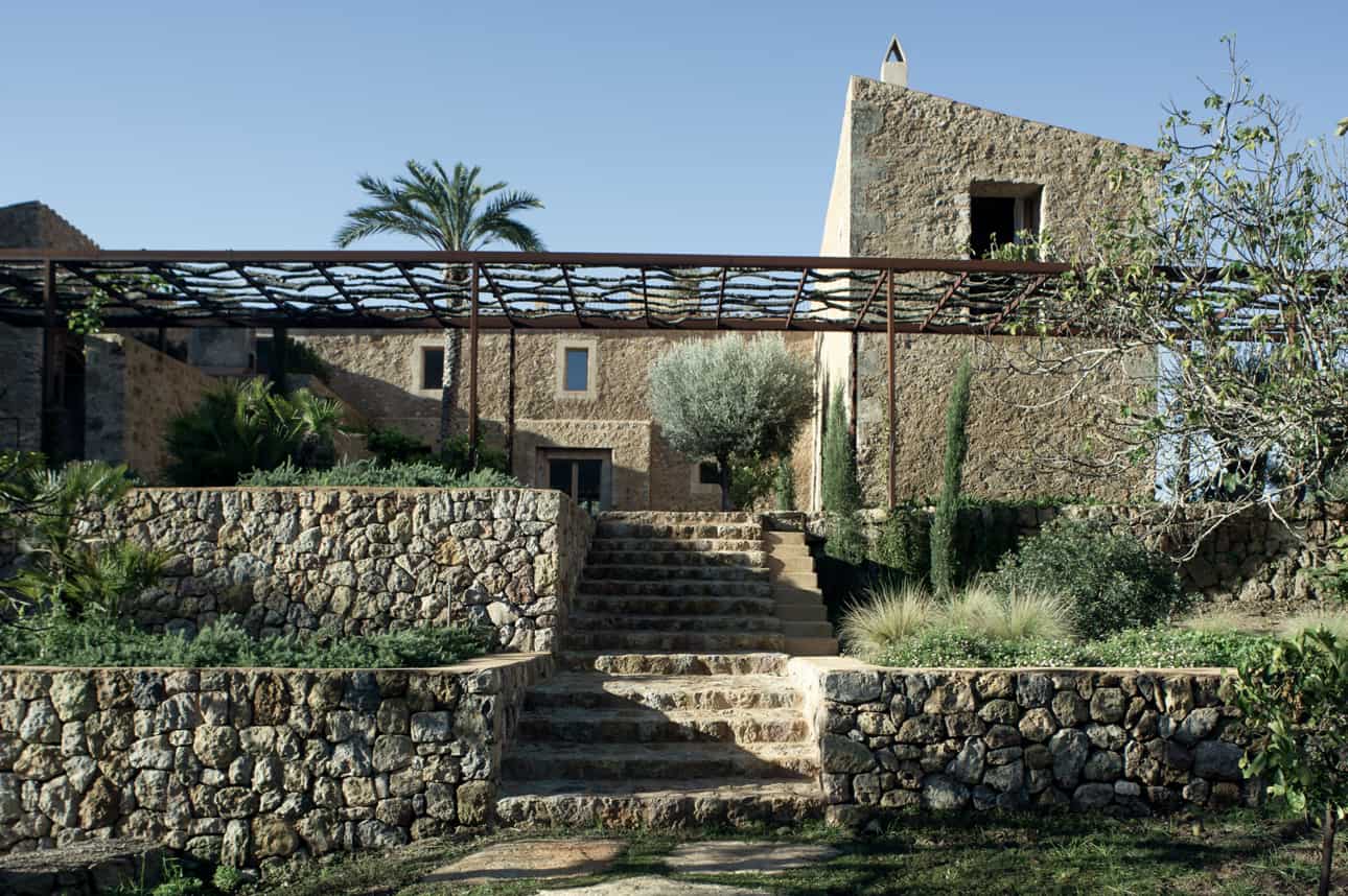 Es Racó d’Artà resort residence entrance with decorative trellis and palm tree garden