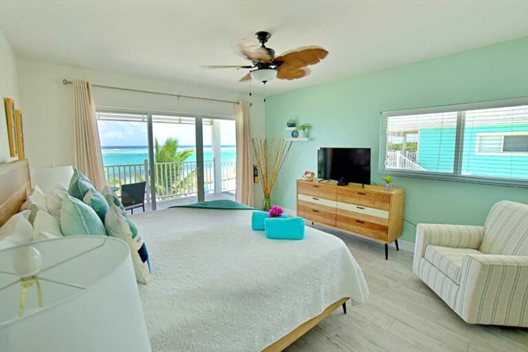 Blue Iguana guest room king bed facing dresser with tv and plush chair