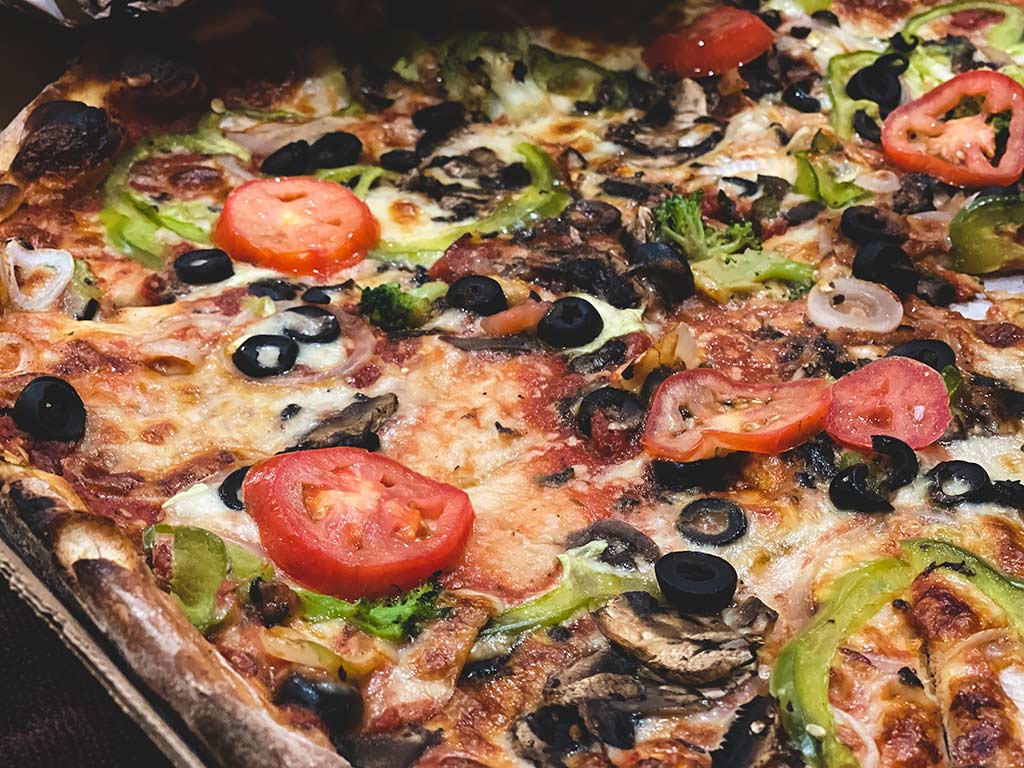 Pizza cubierta con una variedad de verduras.