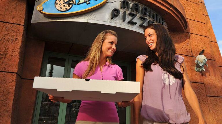 Mujeres caminando con una caja de pizza