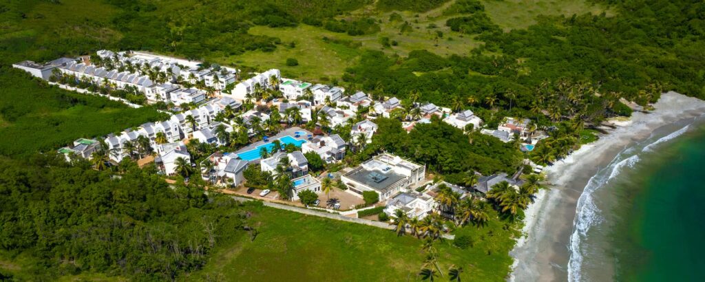 Aerial view of the Cap Cove Resort property, beach, villas, and pool