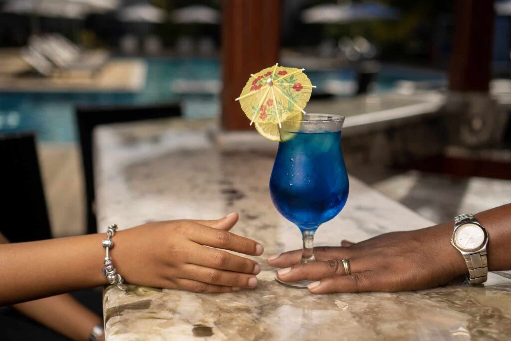 Camarero dando una bebida tropical a un huésped en el bar junto a la piscina de Cap Cove Resort