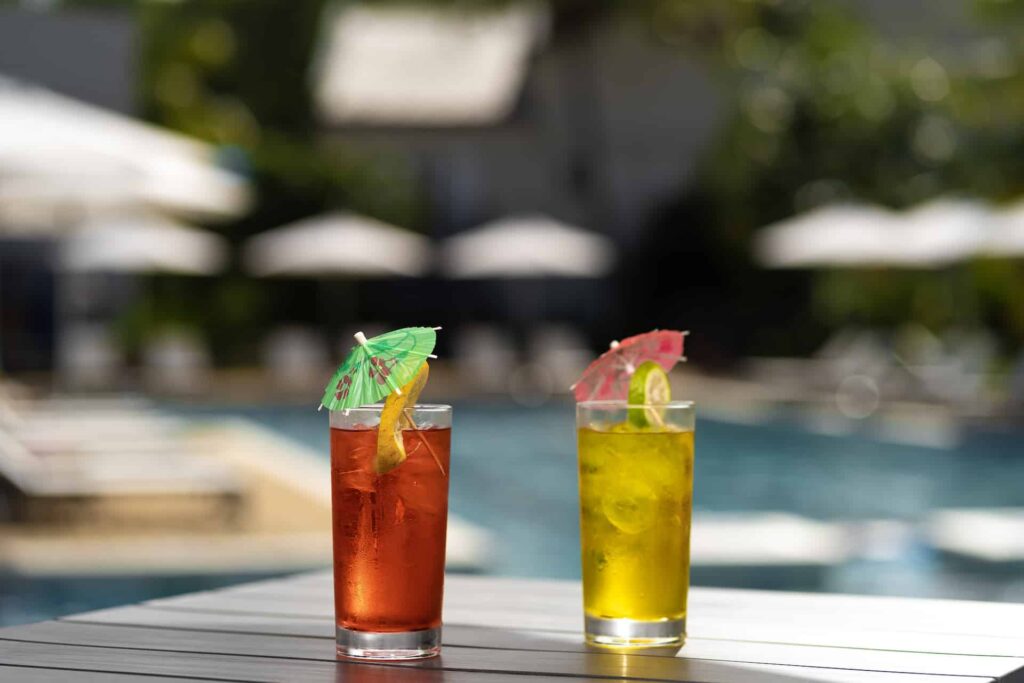 Bebidas tropicales con sombrillas en una mesa junto a la piscina