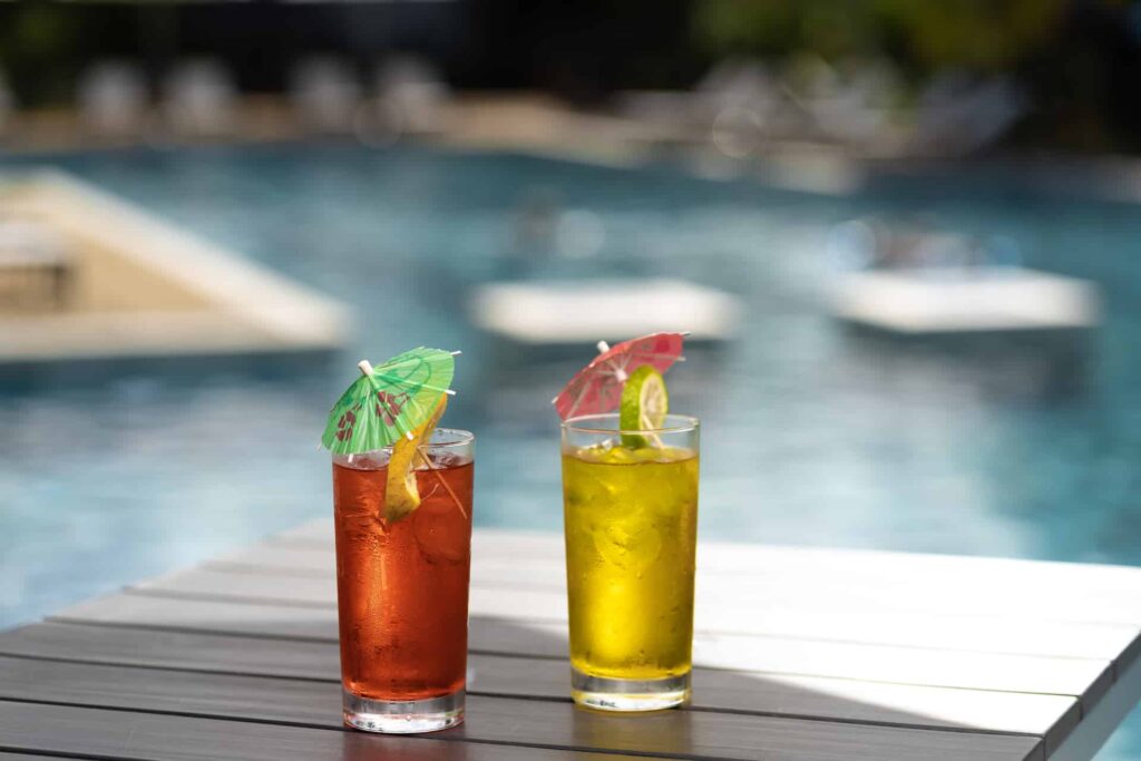 Tropical drinks with umbrellas on a poolside table at Cap Cove Resort.