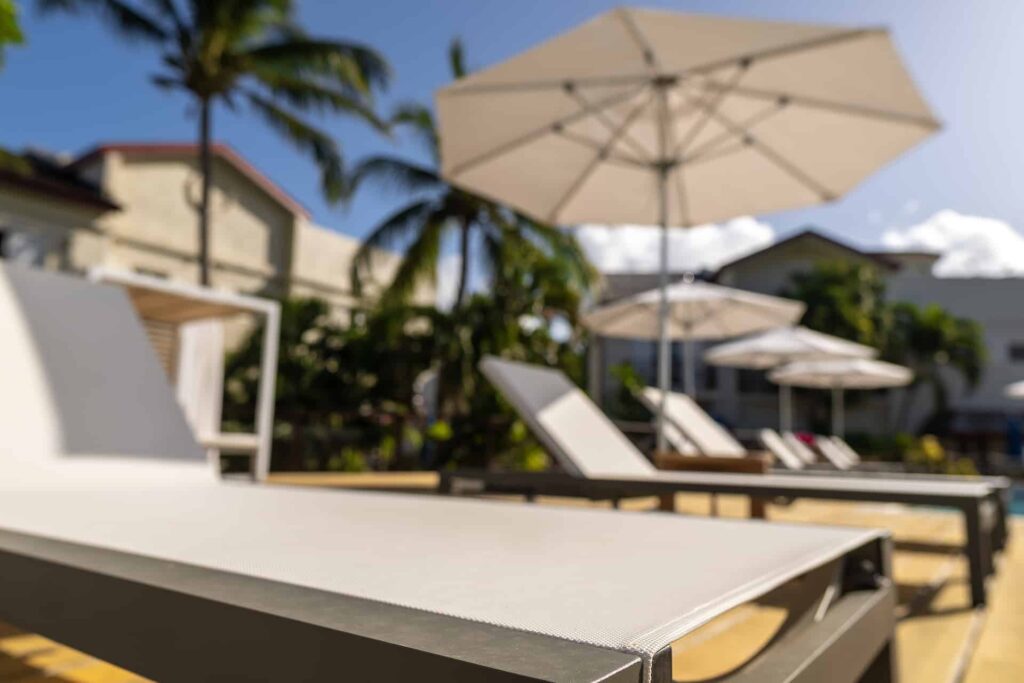 Sun lounger under an umbrella next to the Cap Cove Resort pool