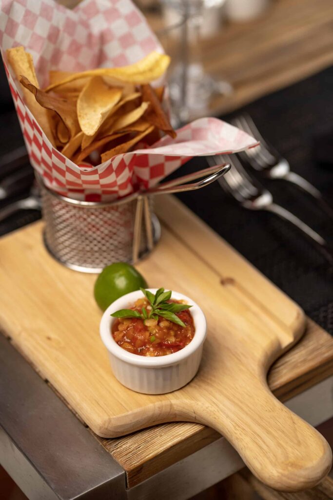 Chips, salsa, and a lime on a mini cutting board