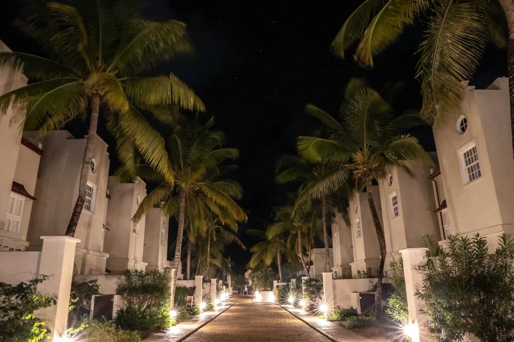 Pasarela iluminada por la noche en Cap Cove Resort bordeada de palmeras