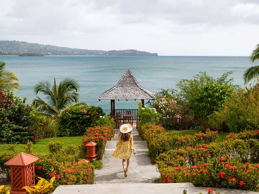 Woman walking on a garden path with the ocean in the background