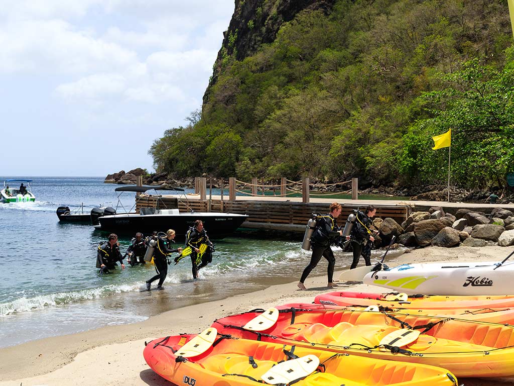Activities: Group of scuba divers emerging from the ocean onto a beach