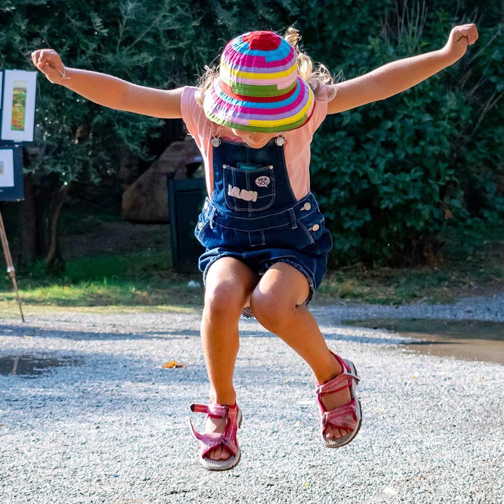 Young girl jumping on a gravel path