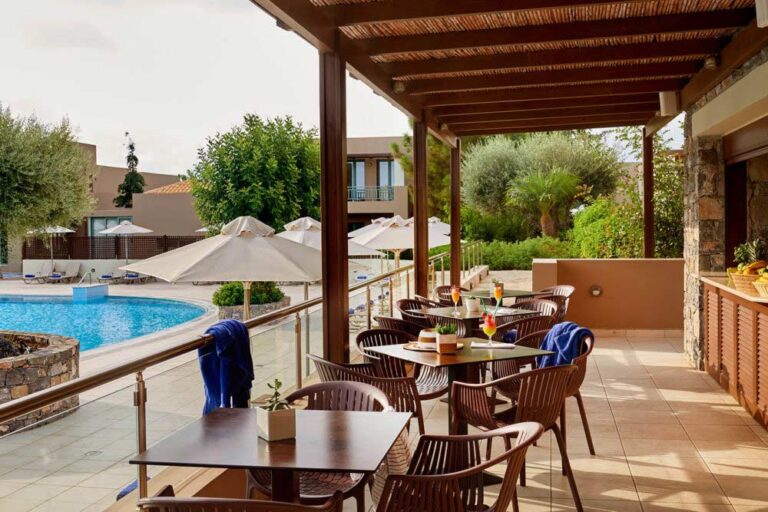 Outdoor tables and chairs on a patio, overlooking a pool