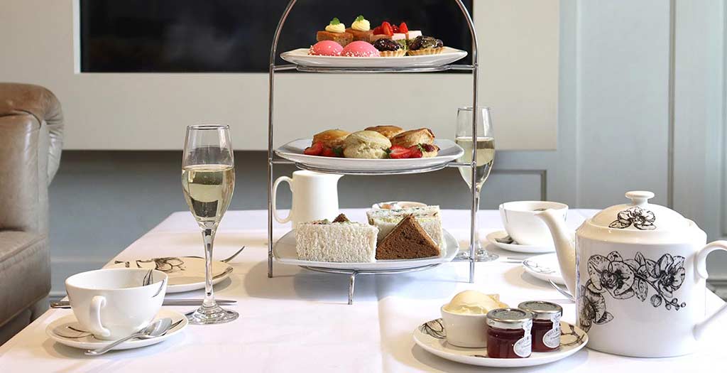 Tiered serving tray with sandwiches, biscuits, and desserts for High Tea
