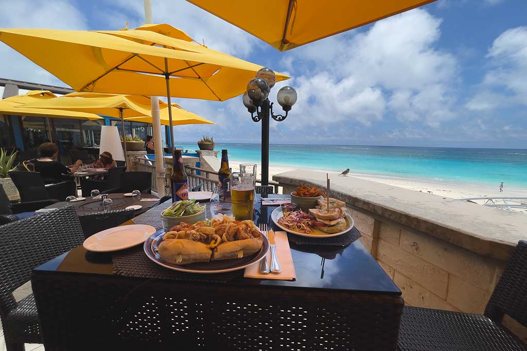 Plated meals set at an outdoor table at a restaurant overlooking a beach