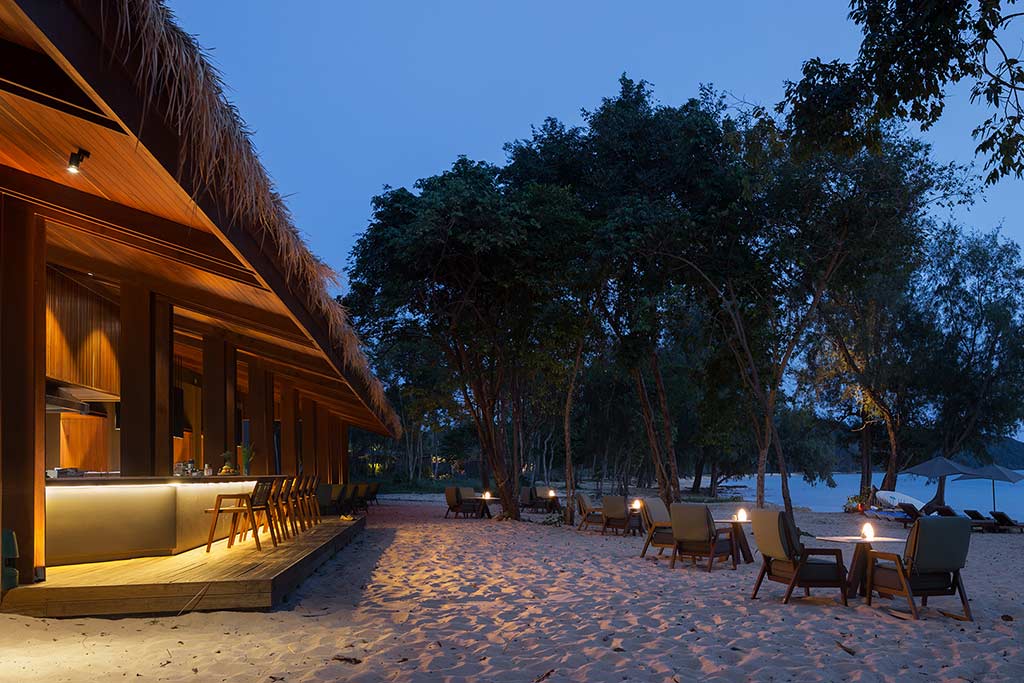 Koh Russey Villas & Resort bar frente al mar y sillas a lo largo de la arena al atardecer