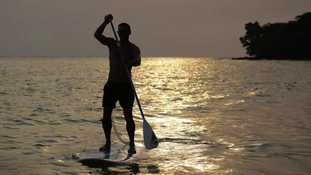 Hombre surf de remo en el océano en Koh Russey Villas & Resort