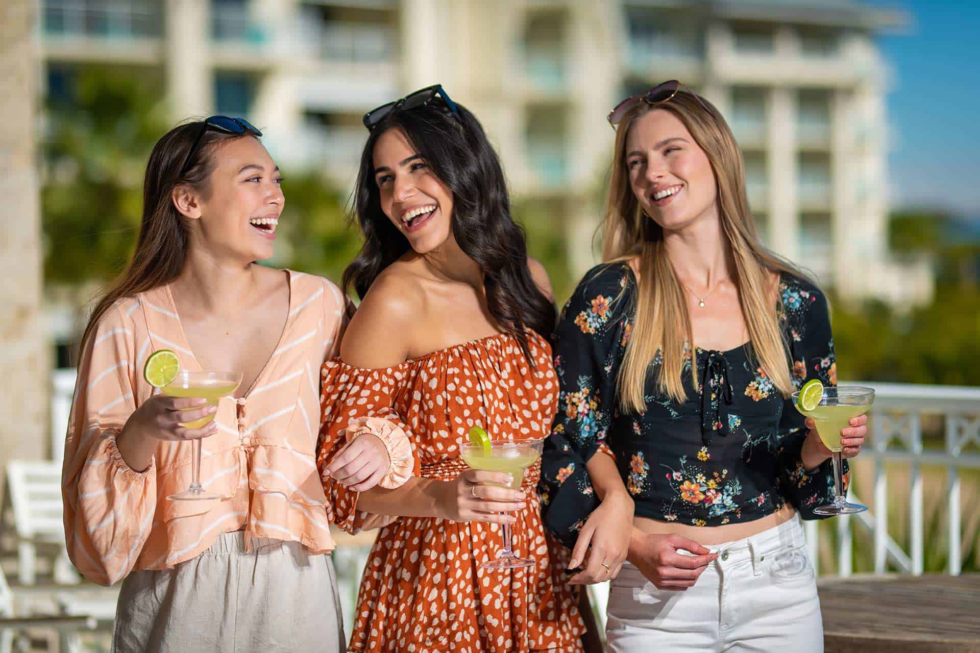 Group of woman laughing while holding margaritas