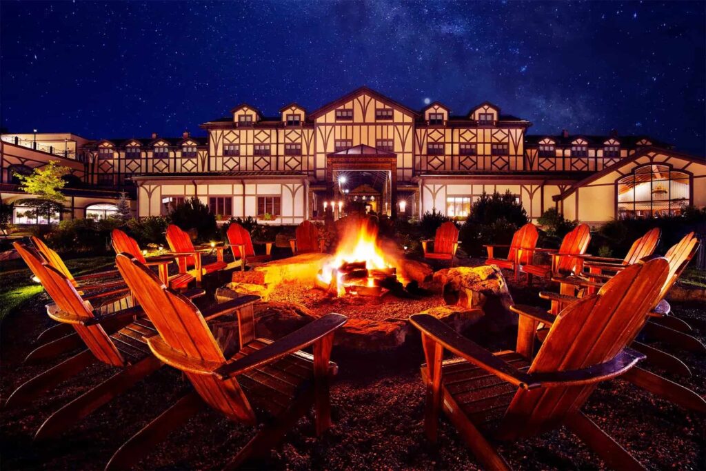 The Lodge at Nemacolin Woodlands Resort lit up at night with outdoor fire pit.