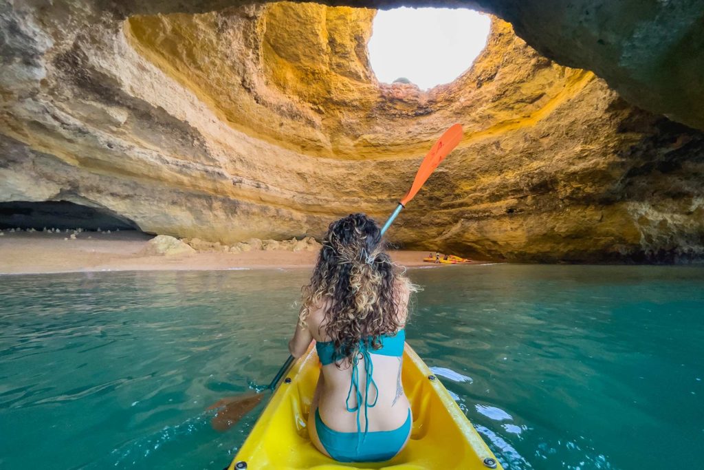 Mujer en un kayak en medio de una cueva en Algarve, Portugal