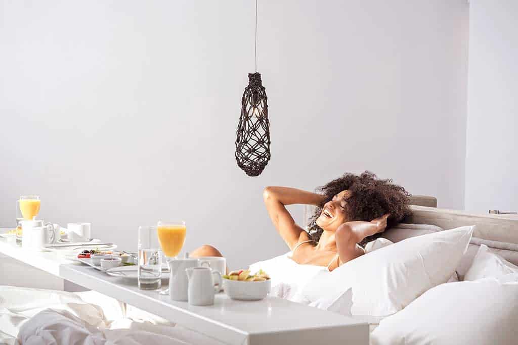 Woman enjoying breakfast in bed at Boheme Mykonos