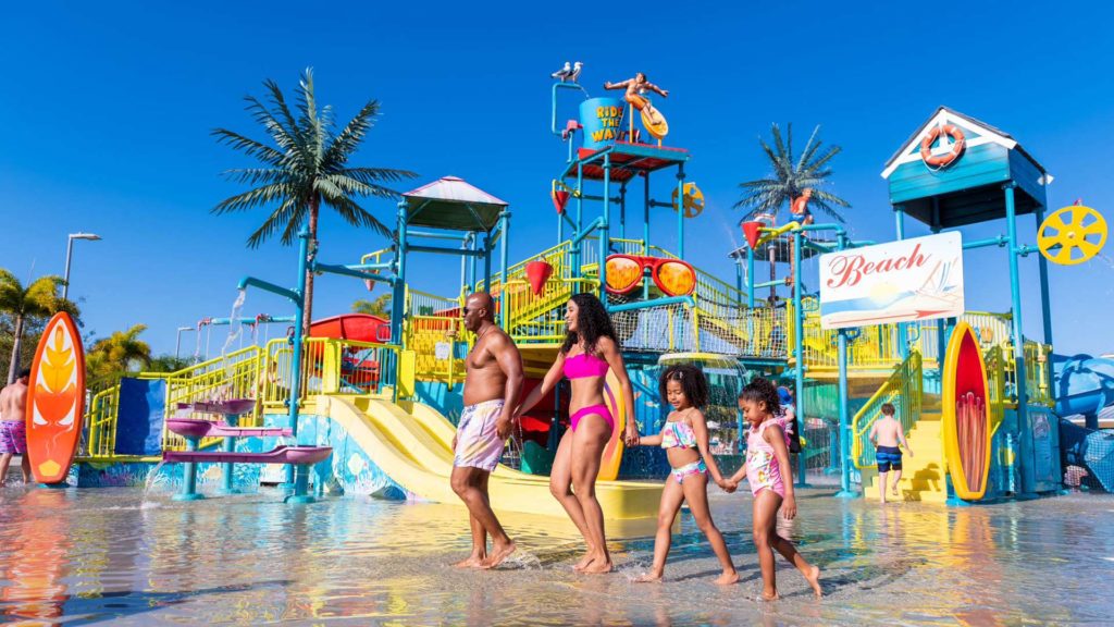 Kinder und Eltern halten sich an den Händen und gehen durch die Encore Resort im Wasserpark La Réunion