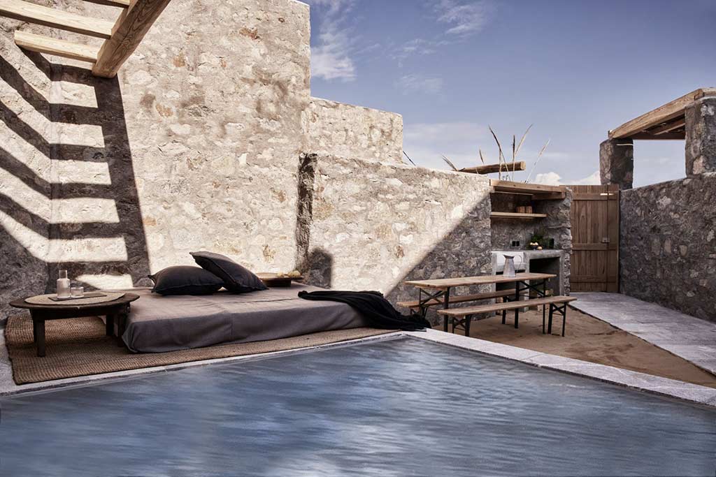 Nomad Mykonos - Cave Suite piscina al aire libre rodeada de muebles de salón y una mesa de comedor