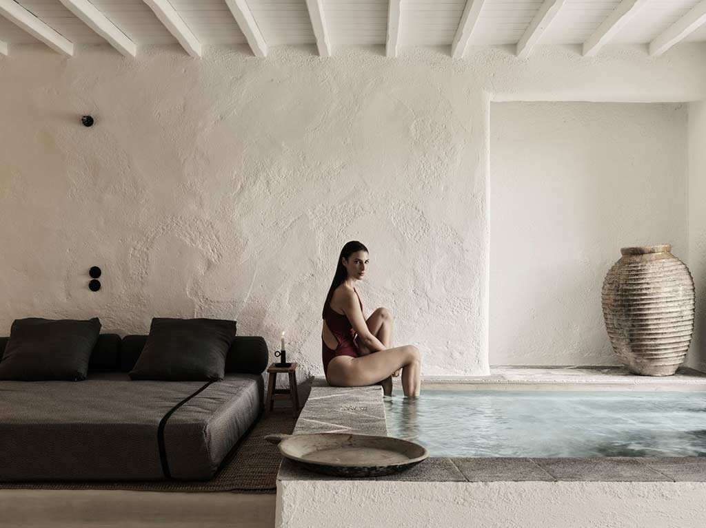 Nomad Mykonos - Mujer sentada al borde de la piscina en la Suite Nomad