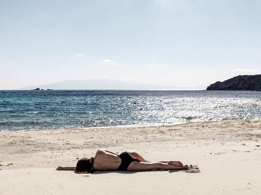 امرأة ترقد على الشاطئ في نوماد ميكونوس