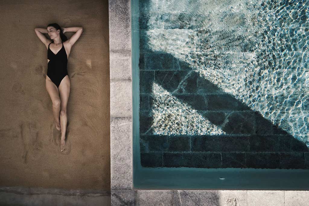 Frau, die auf der Seite eines Pools bei Nomad Mykonos liegt