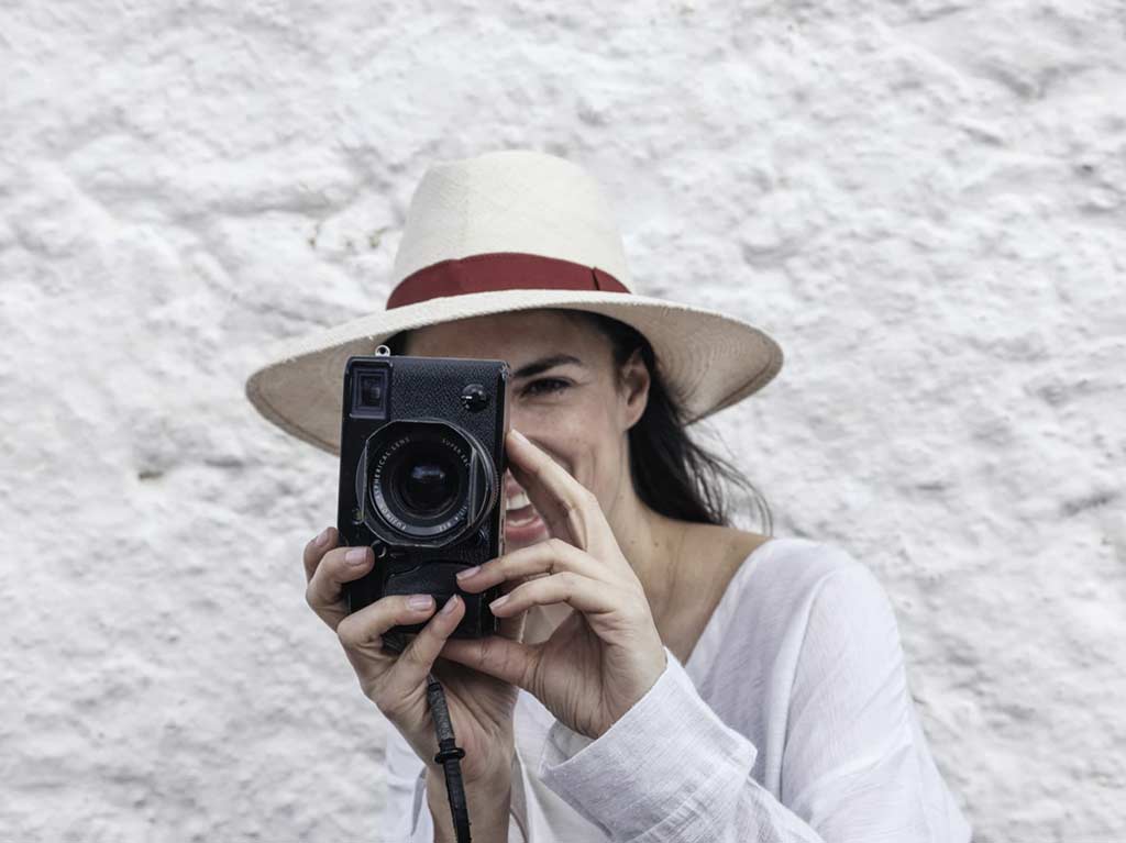 Mujer tomando una foto con una cámara antigua en Nomad Mykonos