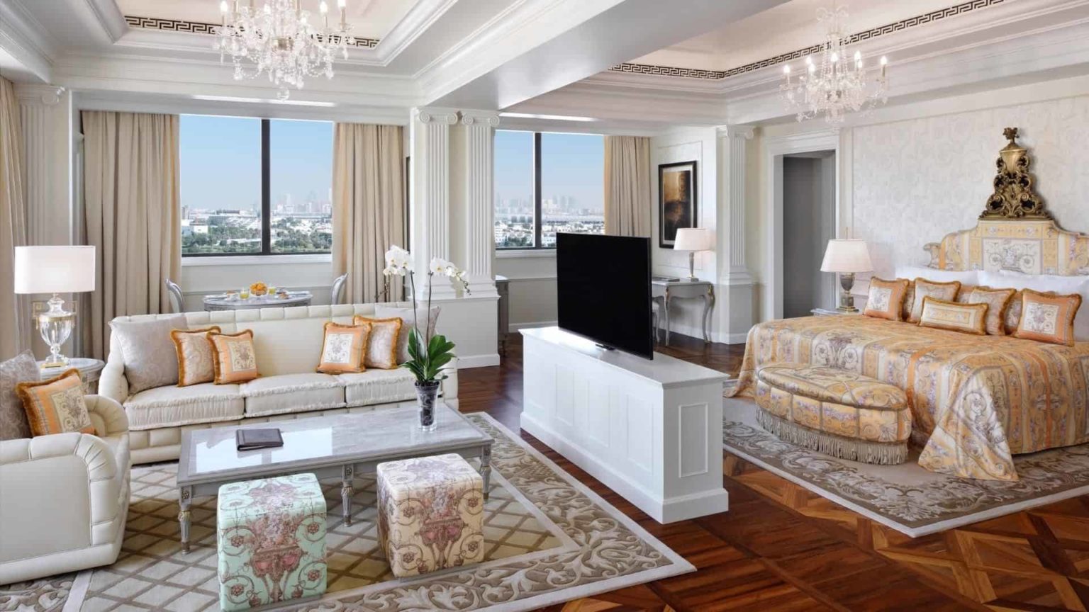 Palazzo Versace Dubai Hotel bedroom suite with king bed, sofa, TV, and panoramic views