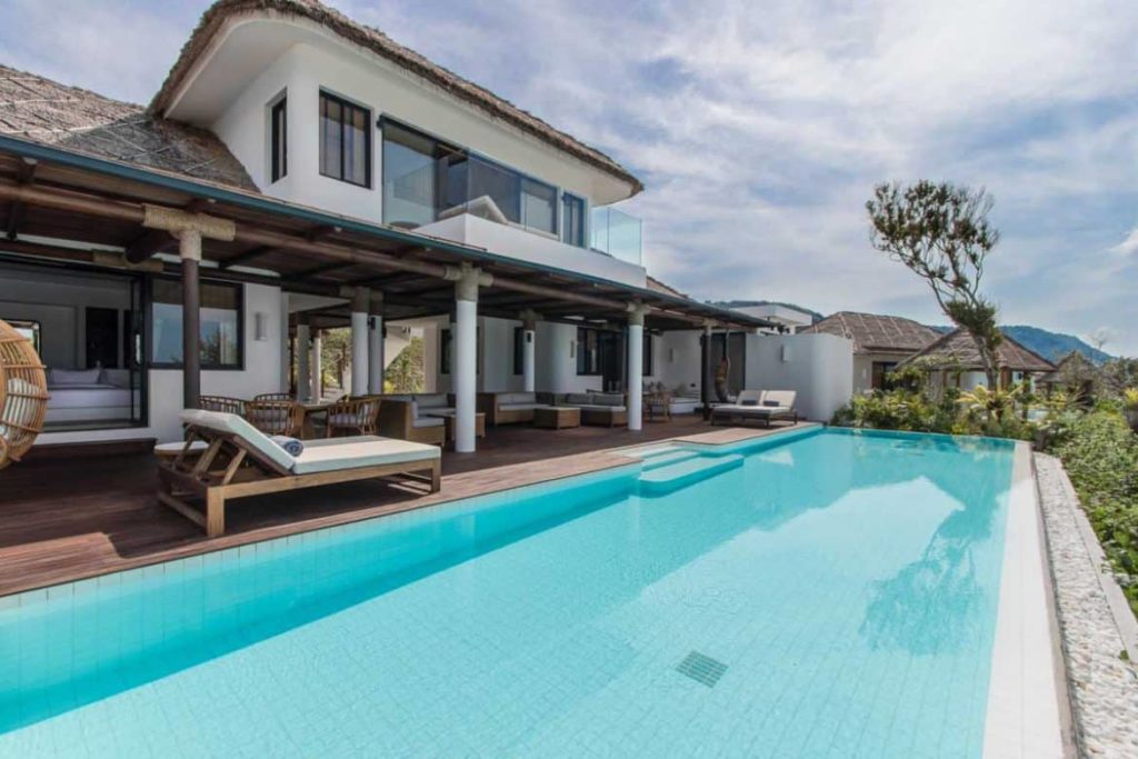 Terraza con sillones, sala de estar, comedor y piscina de la villa privada de tres dormitorios en Royal Sands Koh Rong