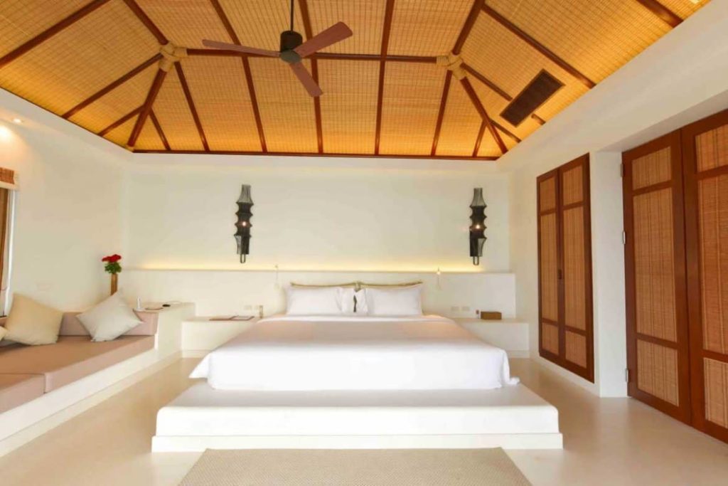 Dormitorio de la villa frente a la playa con cama king size y sala de estar en el Royal Sands Koh Rong