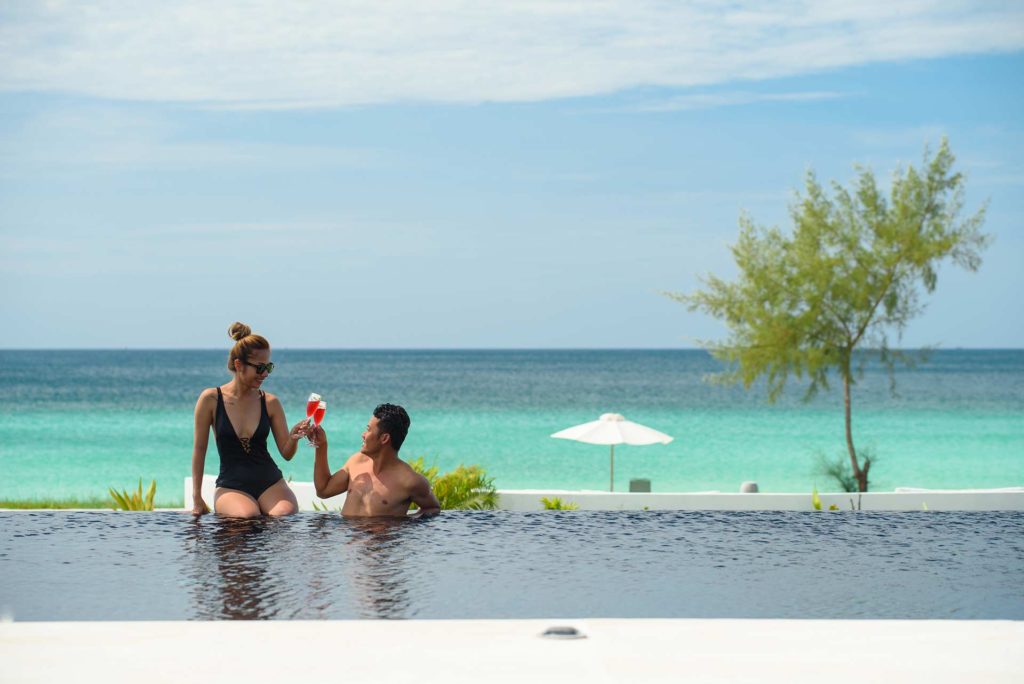 زوجان يستمتعان بالكوكتيلات في المسبح اللامتناهي في Royal Sands Koh Rong