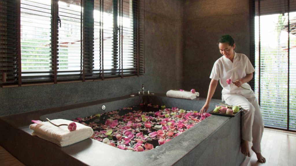 Mujer preparando una bañera de hidromasaje con pétalos de loto en el Royal Sands Koh Rong