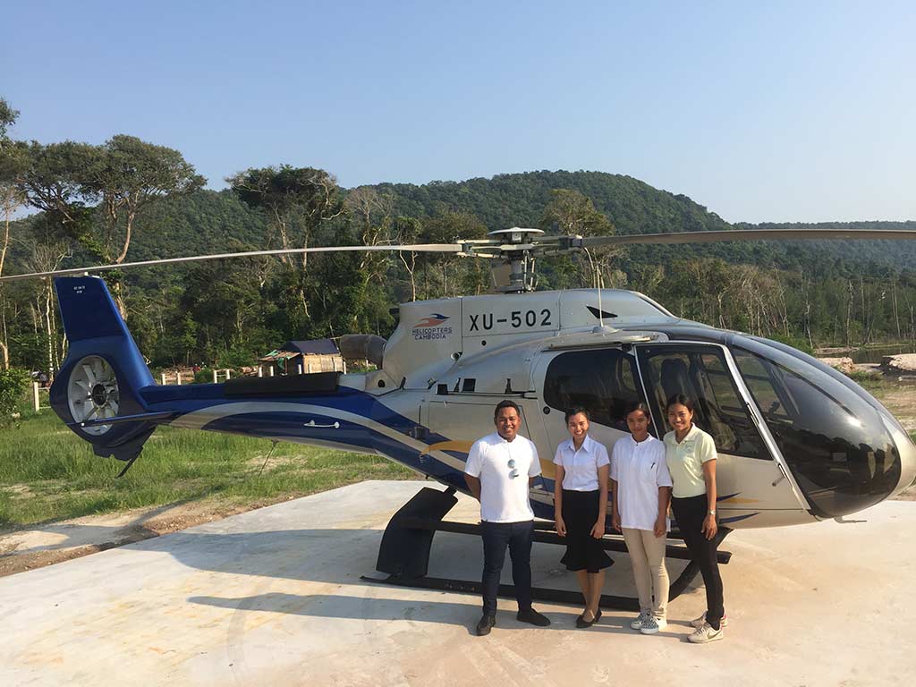 Miembros del personal de Royal Sands Koh Rong parados frente a un helicóptero