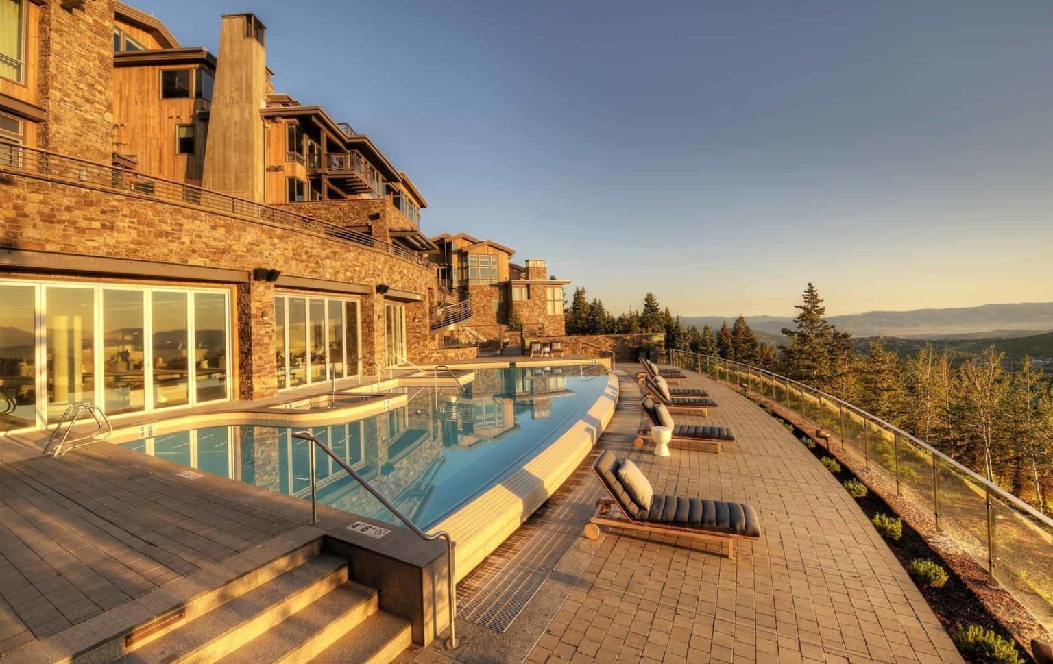 Stein Eriksen Residences exterior infinity pool and sun loungers overlooking the mountains