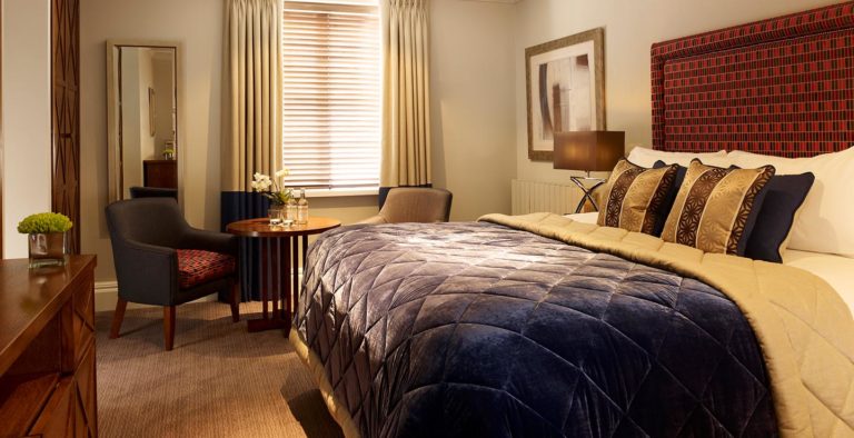 Dormitorio de lujo con cama King y sala de estar en Arden Hotel