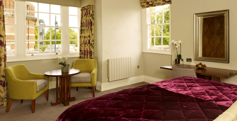 Dormitorio principal con cama King, sala de estar y estación de trabajo en Arden Hotel