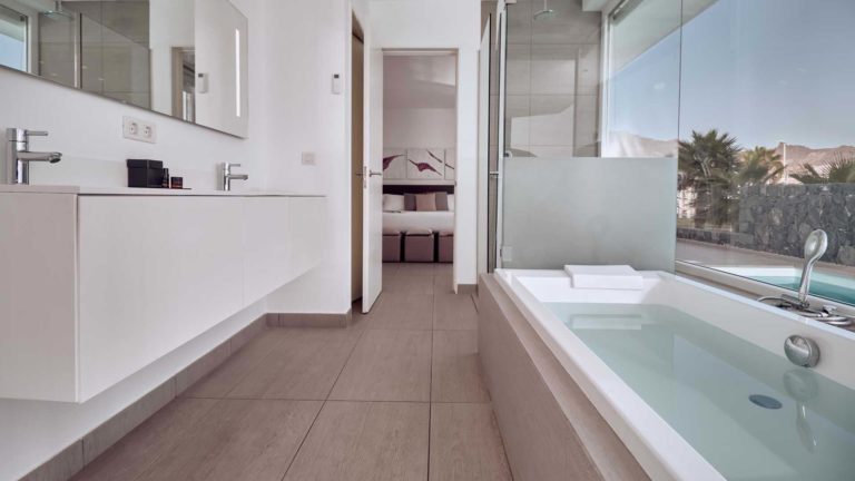 Divinity Mar suite bathroom with separate tub and rain shower, overlooking outdoor pool | Baobab Suites