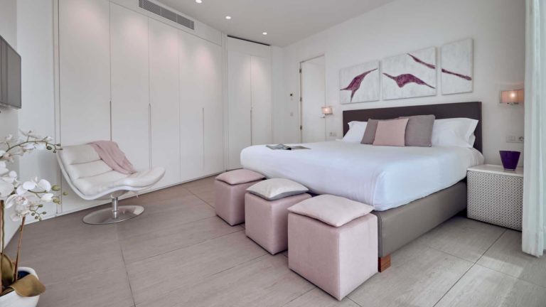 Dormitorio en suite Divinity Mar con cama doble, sala de estar y armarios | Suites Baobab