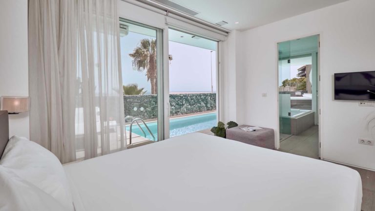 Divinity Mar suite bedroom with double bed, overlooking outdoor pool | Baobab Suites