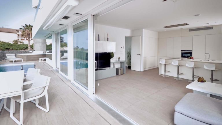 Sala de estar y cocina de concepto abierto de la suite Divinity Mar con puertas corredizas abiertas a la terraza privada | Suites Baobab