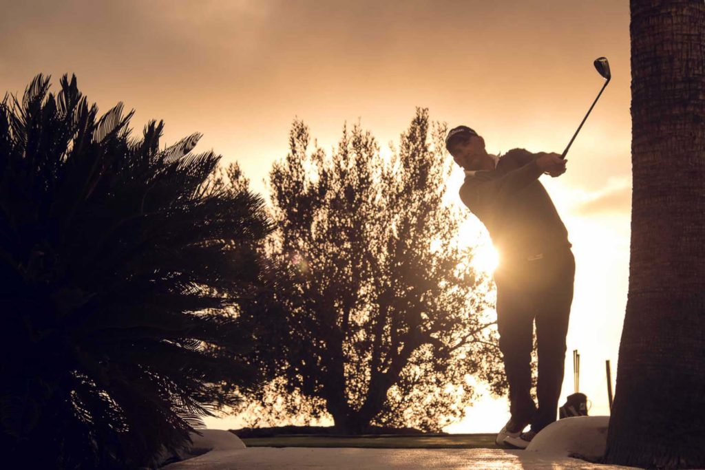 Man playing a round of golf at sunset