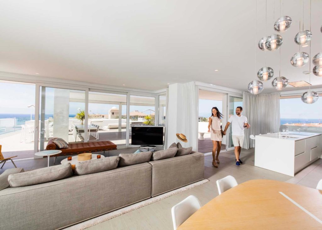 Pareja de la suite Infinity Euphoria entrando a la sala de estar de concepto abierto | Suites Baobab