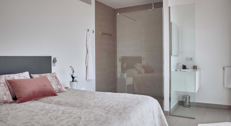 Dormitorio de la suite Infinity Indulgence y baño en suite con ducha de efecto lluvia | Suites Baobab