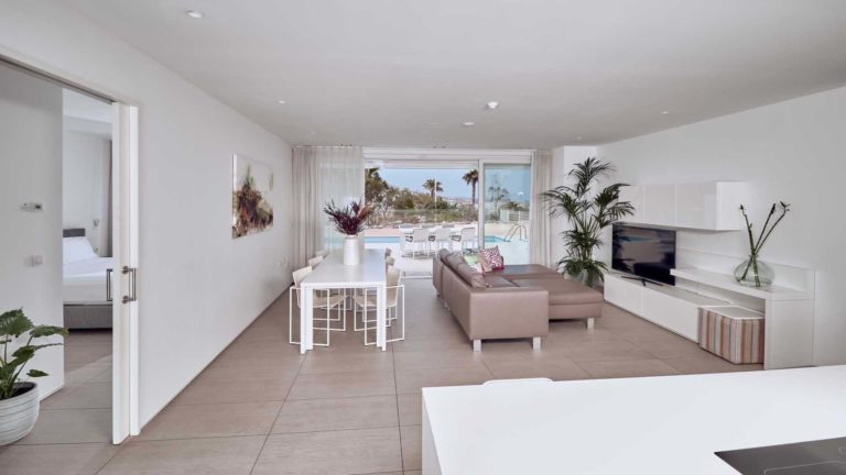 Sala de estar, comedor y cocina de concepto abierto de la suite Infinity Rio con puertas corredizas que conducen a la terraza | Suites Baobab