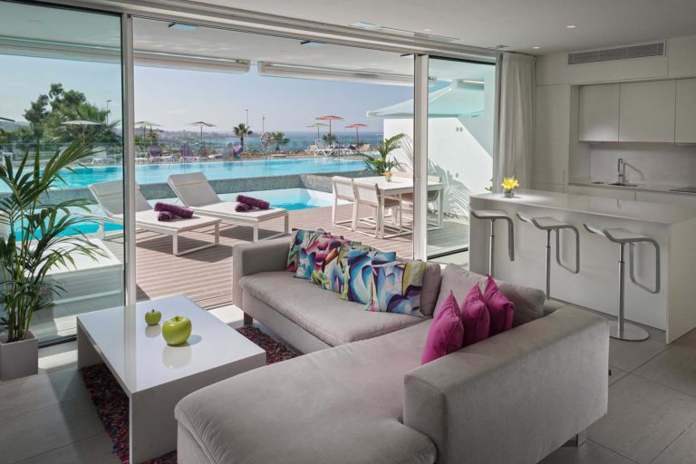 Sala de estar y cocina de concepto abierto de la suite Serenity Rio con puertas corredizas que conducen a la terraza privada | Suites Baobab